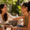 Two friends share a warm, genuine moment of connection on a sun-drenched California patio with plants and soft afternoon light around them