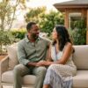A couple sits close together on a bright outdoor patio in soft California light, listening to each other in a warm, connected moment