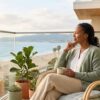 A person sits thoughtfully on a light-filled balcony overlooking a calm Southern California view, taking a reflective pause