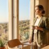 A composed professional stands by a sunlit window in a modern Southern California workspace, looking calm and grounded