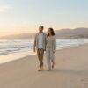 A couple walks along a quiet Southern California beach at sunset, close together with relaxed, easy body language